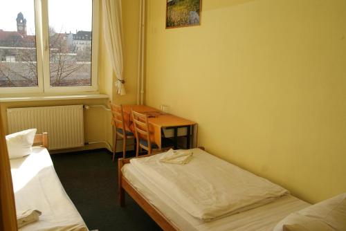 a room with two beds and a table and a window at Happy Go Lucky Hotel + Hostel in Berlin
