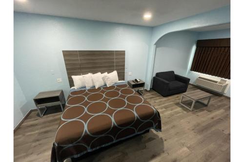 a hotel room with a large bed and a chair at Super Stay Inn By OYO Humble IAH East in Humble