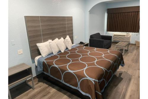 a hotel room with a large bed and a chair at Super Stay Inn By OYO Humble IAH East in Humble