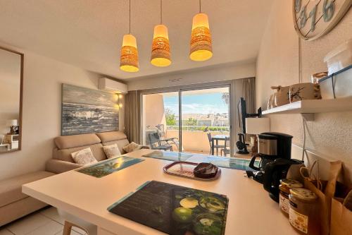 une cuisine et un salon avec une table dans une pièce dans l'établissement LE MAYFLOWER - Appartement cosy dans résidence de standing avec piscine, au Grau-du-Roi
