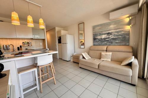 un salon avec un canapé et une cuisine dans l'établissement LE MAYFLOWER - Appartement cosy dans résidence de standing avec piscine, au Grau-du-Roi