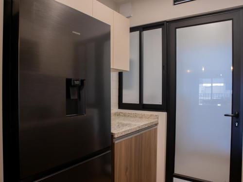 a black refrigerator in a kitchen with a window at Aguirre By Wynwood House in Lima