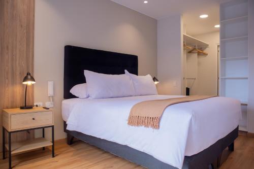 a bedroom with a large white bed and a night stand at Aguirre By Wynwood House in Lima