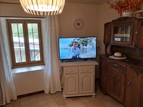 telewizor siedzący na stojaku w pokoju z oknem w obiekcie Les VIGNEAUX Hautes Alpes, Appartement 4 personnes, avec belle terrasse panoramique w mieście Les Vigneaux