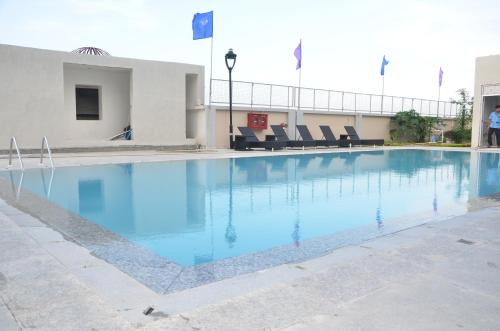 a large swimming pool with blue water in front of a building at Maha Bodhi Hotel.Resort.Convention Centre in Bodh Gaya