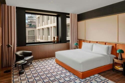 a bedroom with a bed and a chair and a window at Casa Brera, a Luxury Collection Hotel, Milan in Milan