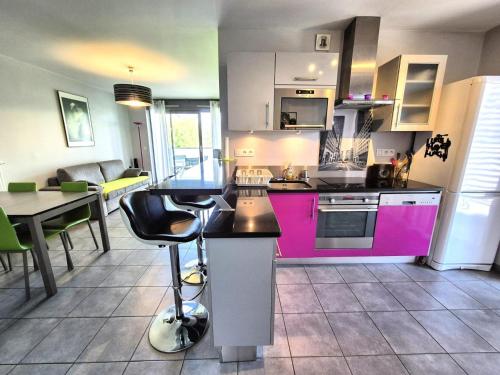 une cuisine avec des placards roses, une table et des chaises dans l'établissement Résidence L'eden Cap - Charmant 2 pièces avec emplacement idéal au bord du lac ! MAE-0394, à Aix-les-Bains