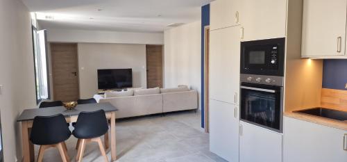 une cuisine et un salon avec une table et des chaises dans l'établissement SUPERBE APPARTEMENT porte de la Cité Médiévale entièrement rénové très bien équipé 6 pers balcon clim parking privé devant, à Sommières