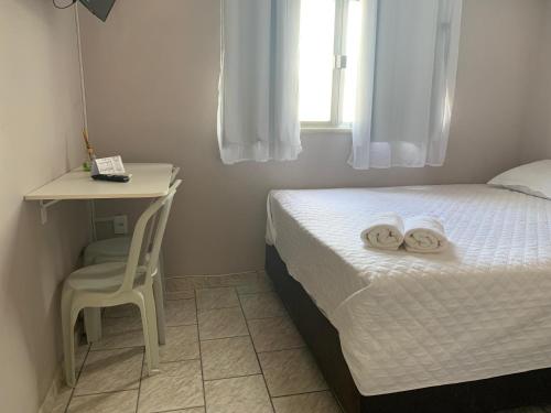 a small bedroom with a bed and a desk and a chair at Casa pôr do sol in São Pedro da Aldeia