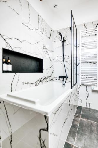 - une salle de bains blanche avec des murs en marbre et un lavabo dans l'établissement Disney World, à Villeneuve-le-Comte