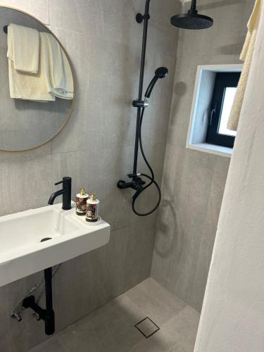 a bathroom with a shower with a sink and a mirror at The Hideaway in Arminou