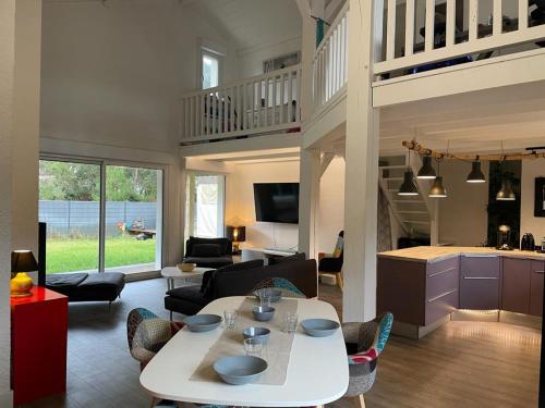 un salon avec une table et des chaises blanches et une cuisine dans l'établissement Villa grands pins et spa, à Soustons