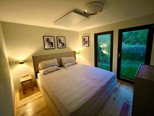 a bedroom with a large white bed with two windows at Haus 1 am Grimnitzsee - erstklassiges Design, mit eigenem Garten und nah am See in Joachimsthal