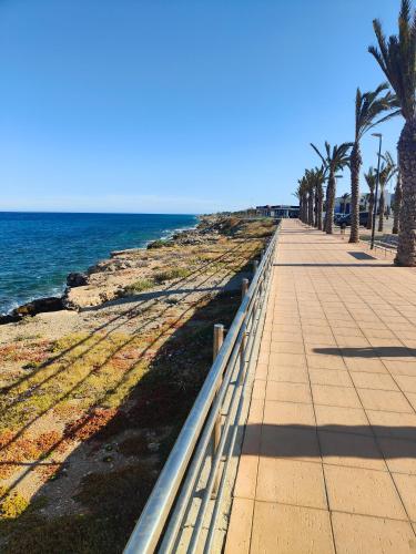 a sidewalk next to the ocean with palm trees at Apartamento Playa del Faro in Garrucha