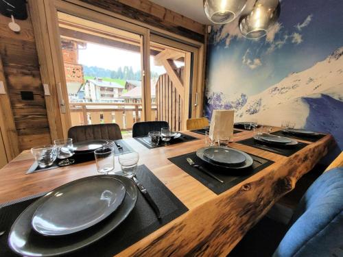 une table en bois avec des assiettes et des verres au-dessus dans l'établissement Résidence Le Confidentiel - appartement neuf en plein centre, 8 personnes MAE-2441, aux Gets