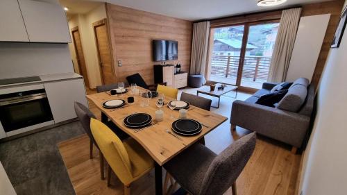une salle à manger et un salon avec une table et des chaises dans l'établissement Résidence Le Stella - Appartement de standing au cœur du village MAE-2571, aux Gets