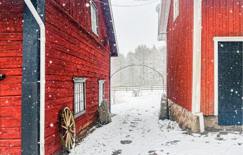 a red barn with a wooden wagon on it in the snow at Awesome Home In Skövde With Sauna in Skövde