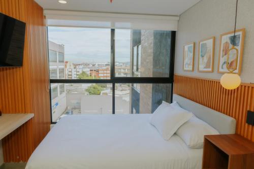 a bedroom with a white bed and a large window at Mini loft en Usaquén cerca la Fundación Santa Fe in Bogotá