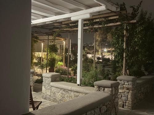 a stone wall with a pergola in a garden at Anais in Mýkonos City
