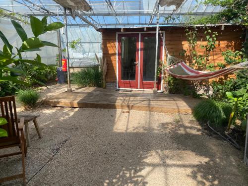 a hammock in front of a house in a greenhouse at Unique Tiny House close to Ams Airport with Hottub in Rijsenhout