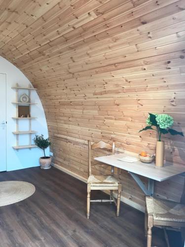 a room with a wooden wall with a table and chairs at Very unique 'tiny house' with Hottub in Rijsenhout