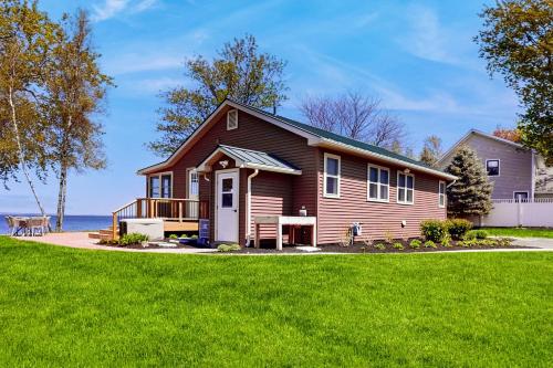 a house with a green lawn in front of the ocean at Thayer Beach Lakehouse in Colchester