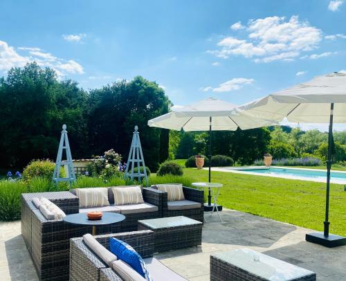 - une terrasse avec des canapés et des parasols à côté de la piscine dans l'établissement Château de la Forge, à Douville