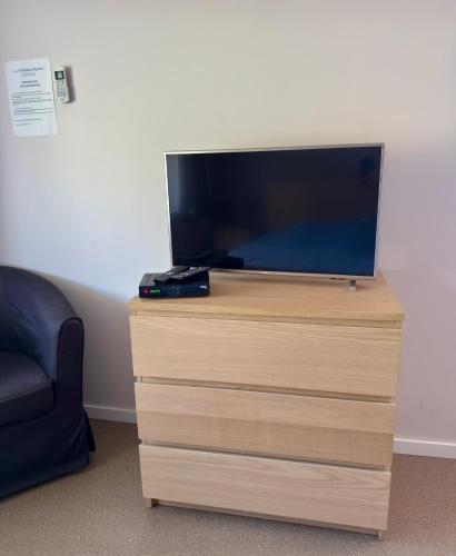 a flat screen tv on a wooden dresser with a chair at Résidence Rachel 23 in Mons