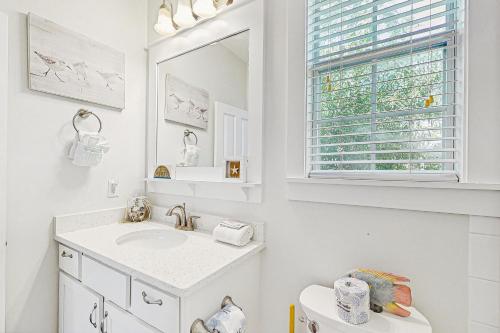 Un baño blanco con lavabo y espejo. en Barefoot Cottages #C56, en Highland View