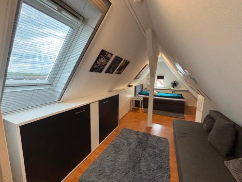 a attic room with a large window and a bed at Moderne deluxe 3-Zi Eigentums- Maisonette-Wohnung IBM Bertrandt Mercedes in Ehningen