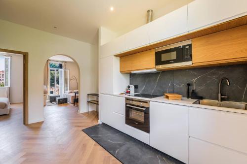 une cuisine avec des armoires blanches et un évier dans l'établissement Elegant 2 pieces avec vue mer aux portes de Monaco, à Beausoleil