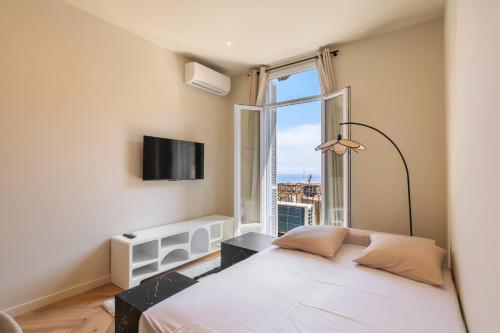une chambre avec un lit blanc et une grande fenêtre dans l'établissement Elegant 2 pieces avec vue mer aux portes de Monaco, à Beausoleil