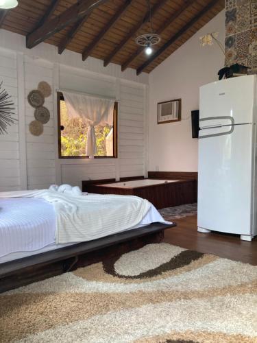 a bedroom with a bed and a white refrigerator at Pousada Coração do Rosa - com Piscina Jacuzzi charme e conforto Pertinho do centrinho do Rosa in Praia do Rosa