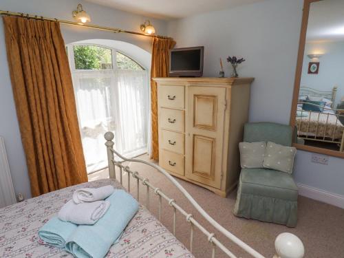 a bedroom with a bed and a dresser and a mirror at The Coach House in Berwick-Upon-Tweed