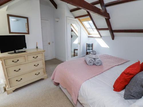 a bedroom with a bed with a television and a dresser at The Coach House in Berwick-Upon-Tweed