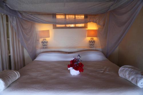 a white bed with a bouquet of red flowers on it at Hotel Bahía de la Luna in Arroyo Cruz