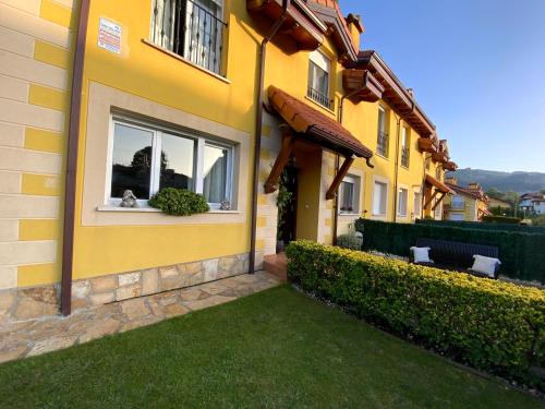a yellow house with a green lawn in front of it at UEFA Bilbao-Castro Urdiales home in Lusa