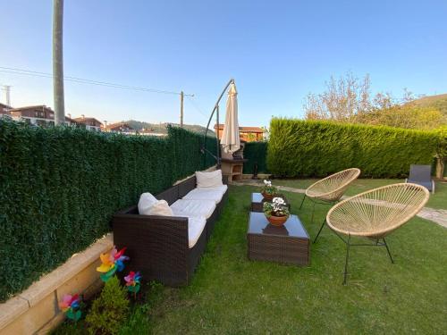 a backyard with a couch and two chairs and a table at UEFA Bilbao-Castro Urdiales home in Lusa