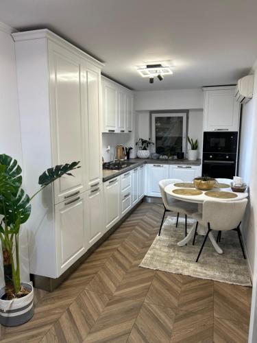 Una cocina con gabinetes blancos y una mesa. en Romina b&b, en Hîrşova