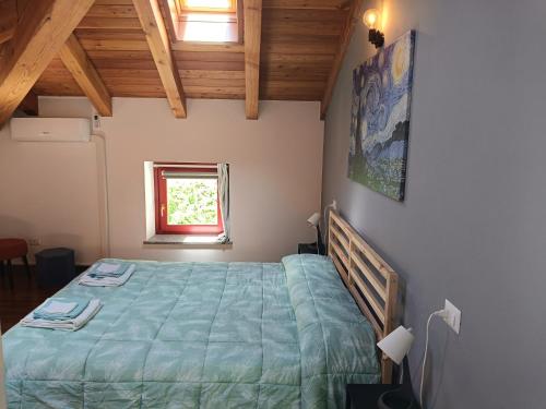 a bedroom with a bed with a green comforter and a window at Liberty House Alps in Châtillon