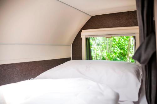 un letto bianco in una stanza con finestra di Bauer Caravan in FKK Camping Solaris a Poreč (Parenzo)