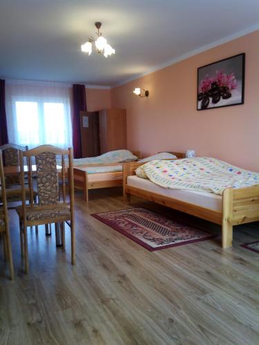 a bedroom with two beds and a table and a chair at Pokoje Pod Łukami in Solina