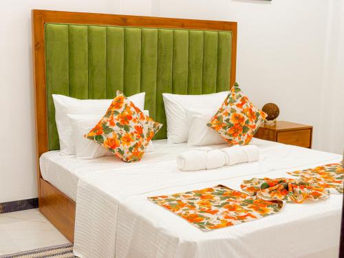 a bed with white sheets and a green headboard at Shelo Transit Hotel in Katunayake