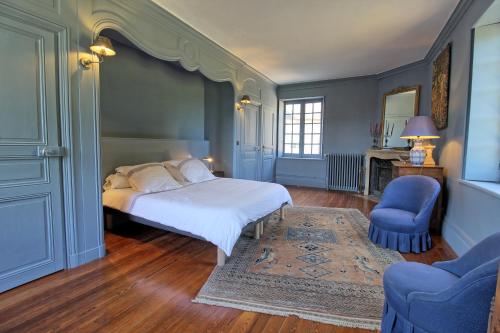 a bedroom with a bed and two blue chairs at Les chambres du Chateau de Farge-Allichamps in Farges-Allichamps