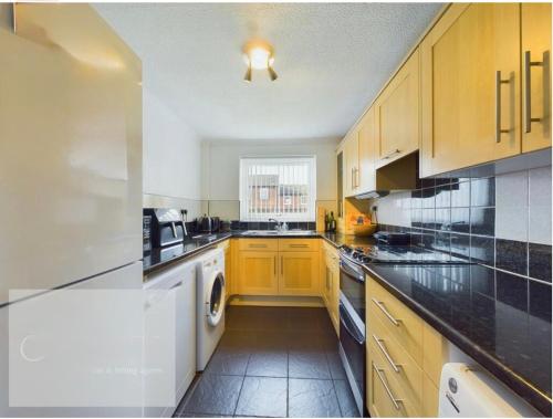 a kitchen with wooden cabinets and black counter tops at The Marlowe Stay in Nottingham