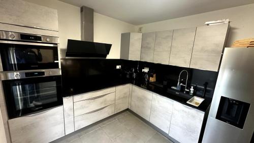 a kitchen with stainless steel appliances and black and white cabinets at Cozy 3 rooms with terrace between Paris & Disney in Noisy-le-Grand