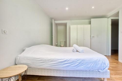 a white bedroom with a large bed and a wooden table at le logis des remparts in Périgueux