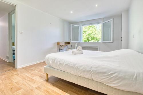 a white bedroom with a large bed and a window at le logis des remparts in Périgueux