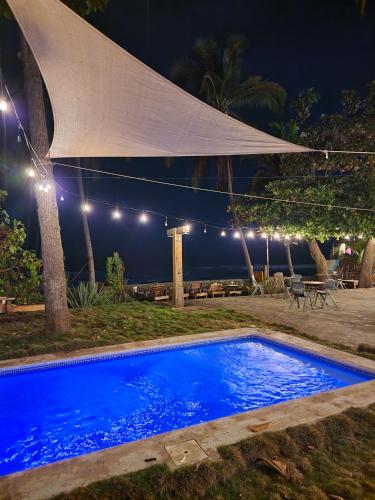 a blue swimming pool at night with a white umbrella at LOOKING2GOOD in El Zonte