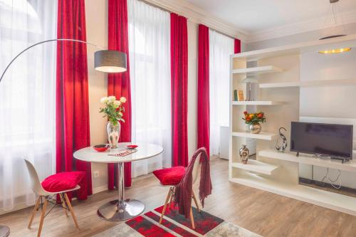 ein Wohnzimmer mit einem Tisch und roten Vorhängen in der Unterkunft Amalienhof Serviced Apartments in Weimar